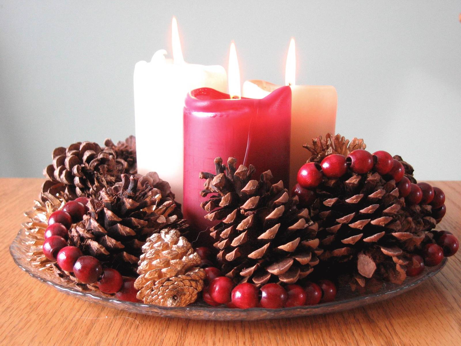 Christmas candles and pinecones on a display plate.